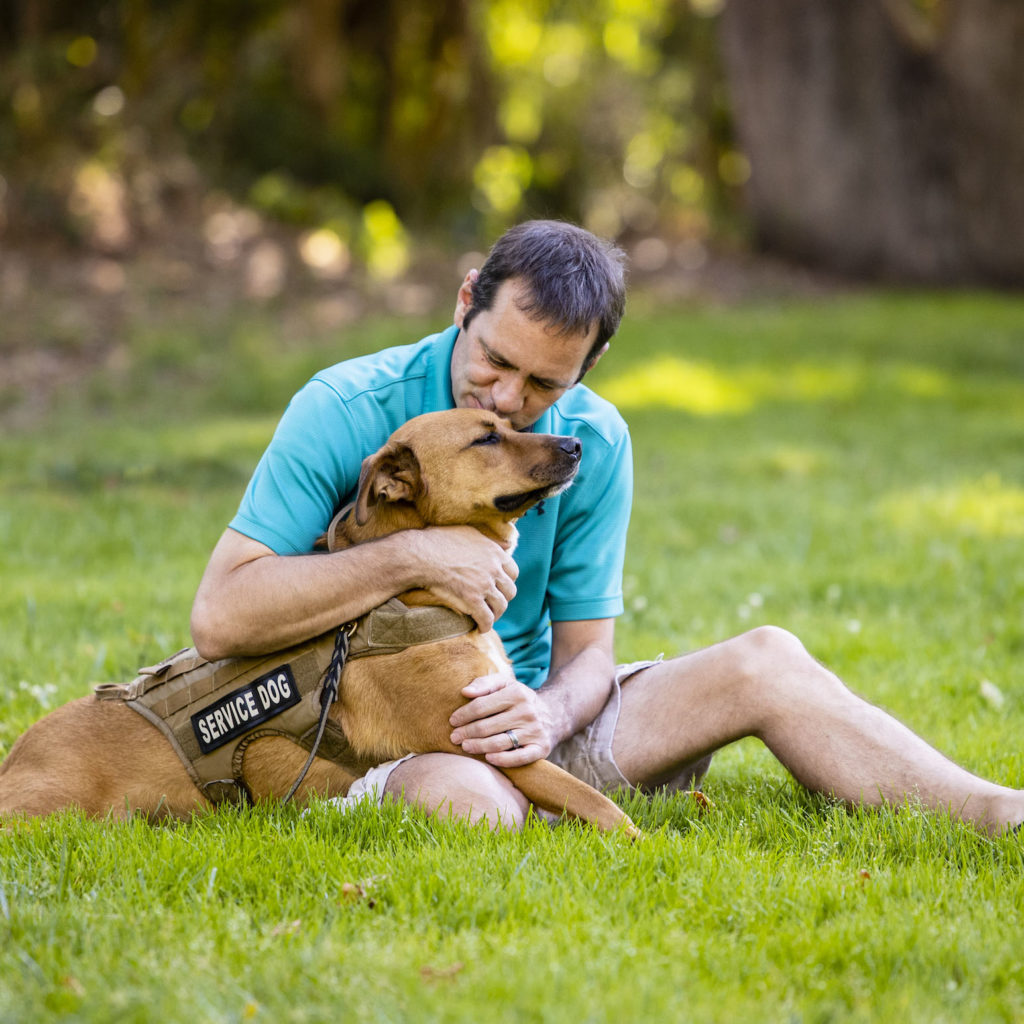 Man hugging service dog